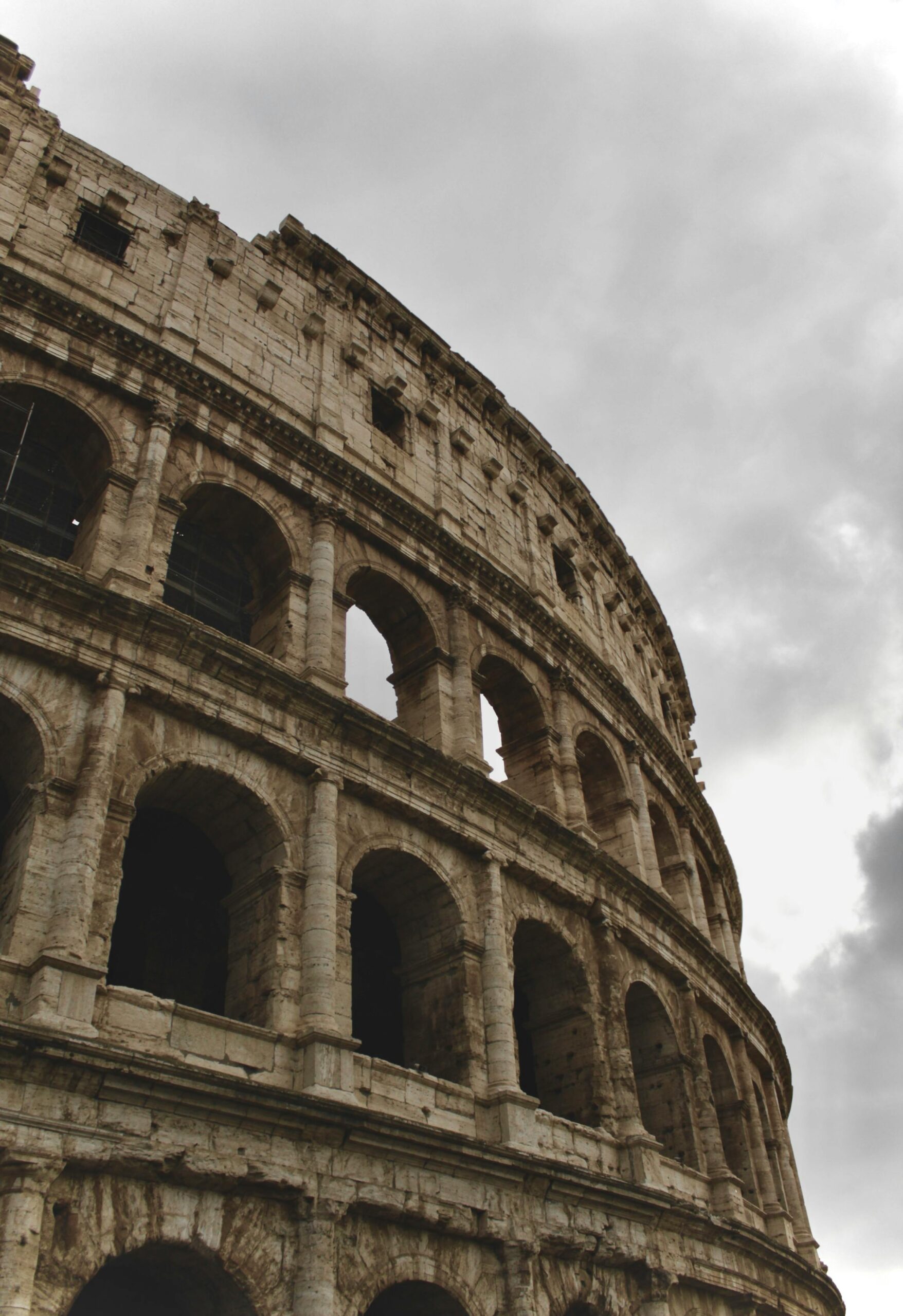 An iconic view of the Colosseum in Rome, Italy, captured under a moody, cloudy sky.