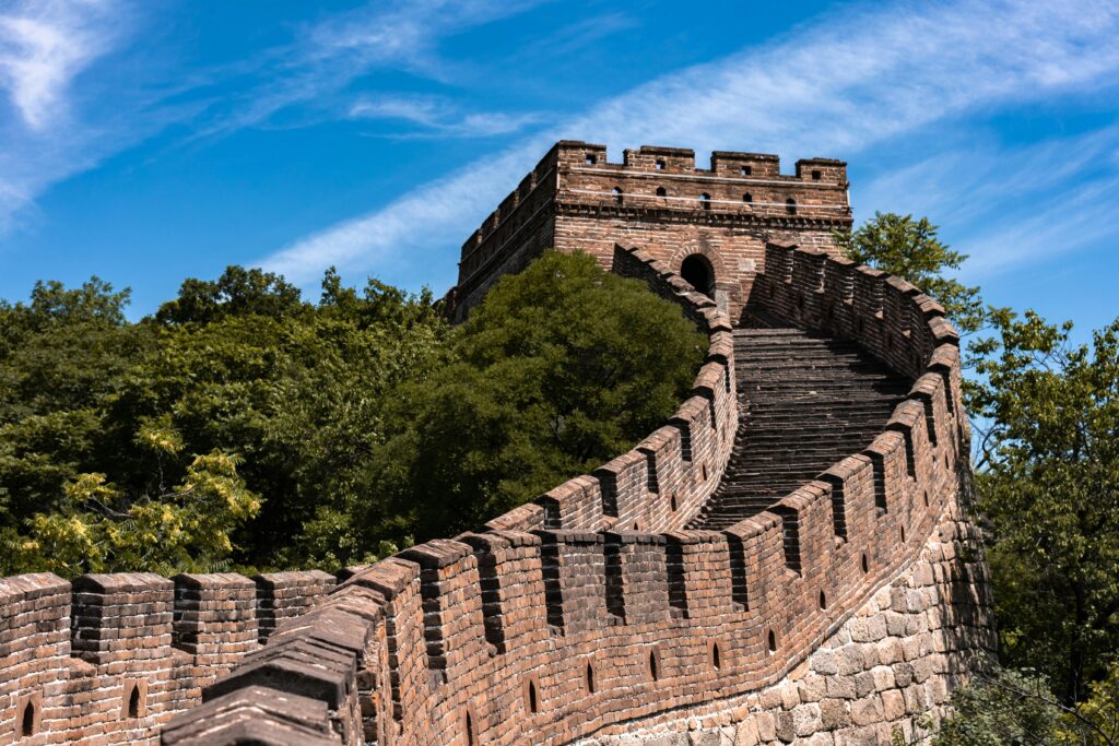 The Great Wall of China surrounded by lush greenery under a clear blue sky.